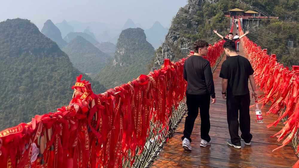 Red prayer ribbons on a suspension bridge above the karst peaks at Zhangjiajie, China